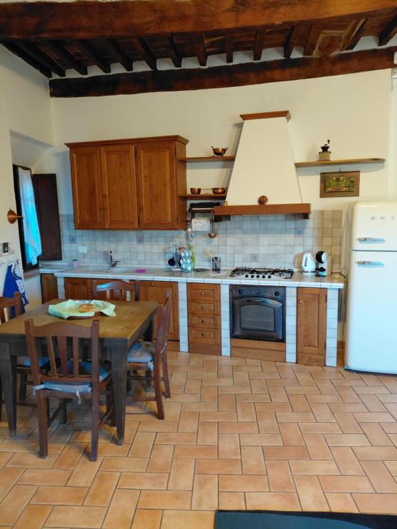 a kitchen with a table and a white refrigerator at La Dimora di Dida in Seggiano