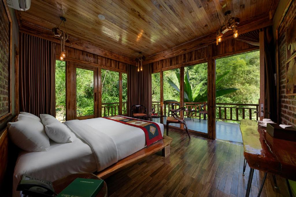 a bedroom with a bed in a room with windows at Asia Tropical Resort and Spa in Làng Coc