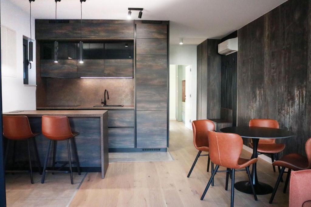 eine Küche mit orangefarbenen Stühlen und einem schwarzen Tisch in der Unterkunft Royal Rest Apartments Karlovac in Karlovac