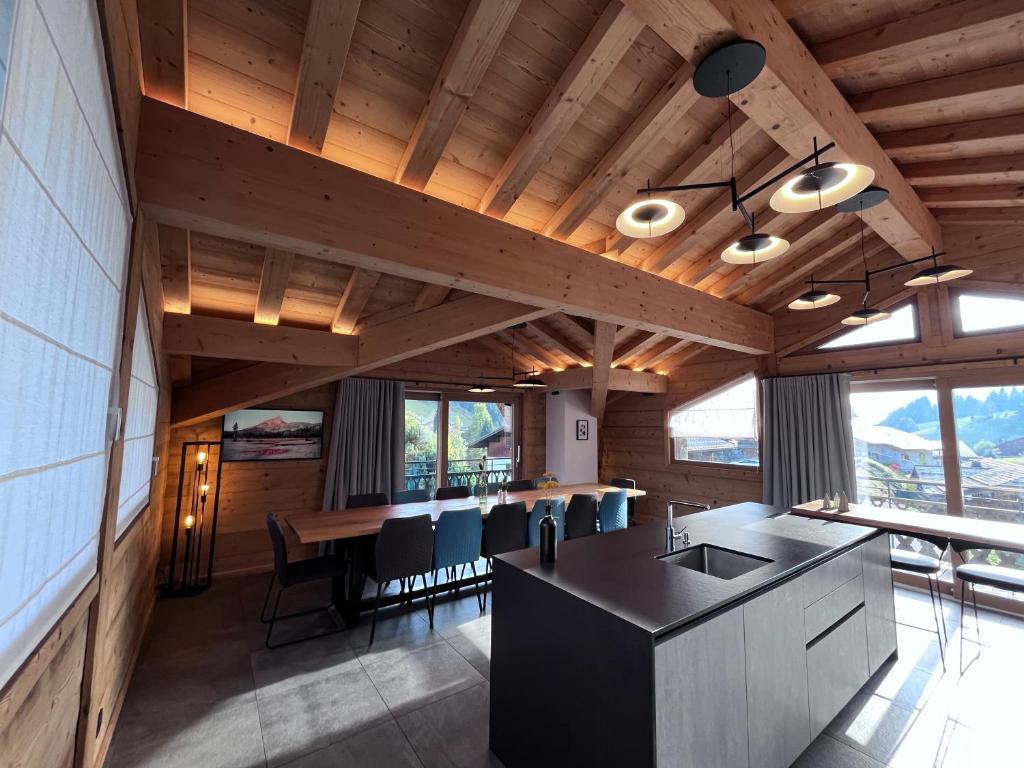 een keuken met houten plafonds en een tafel met stoelen bij Chalet Téléporté in Les Gets