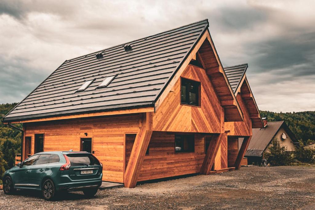 ein vor einem Holzhaus geparktes Auto in der Unterkunft Chałpy H700 in Koszarawa