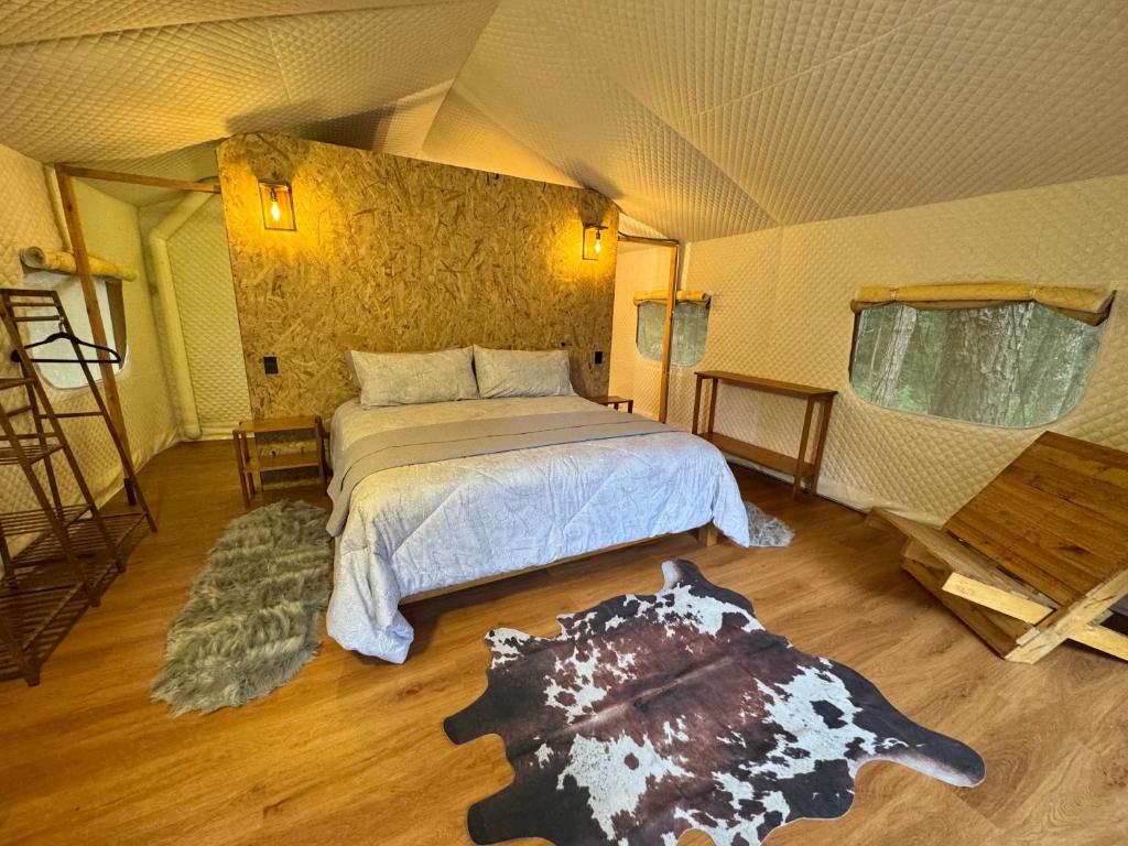 a bedroom with a bed and a rug in a room at Lattitude Glamp Avandaro in Valle de Bravo