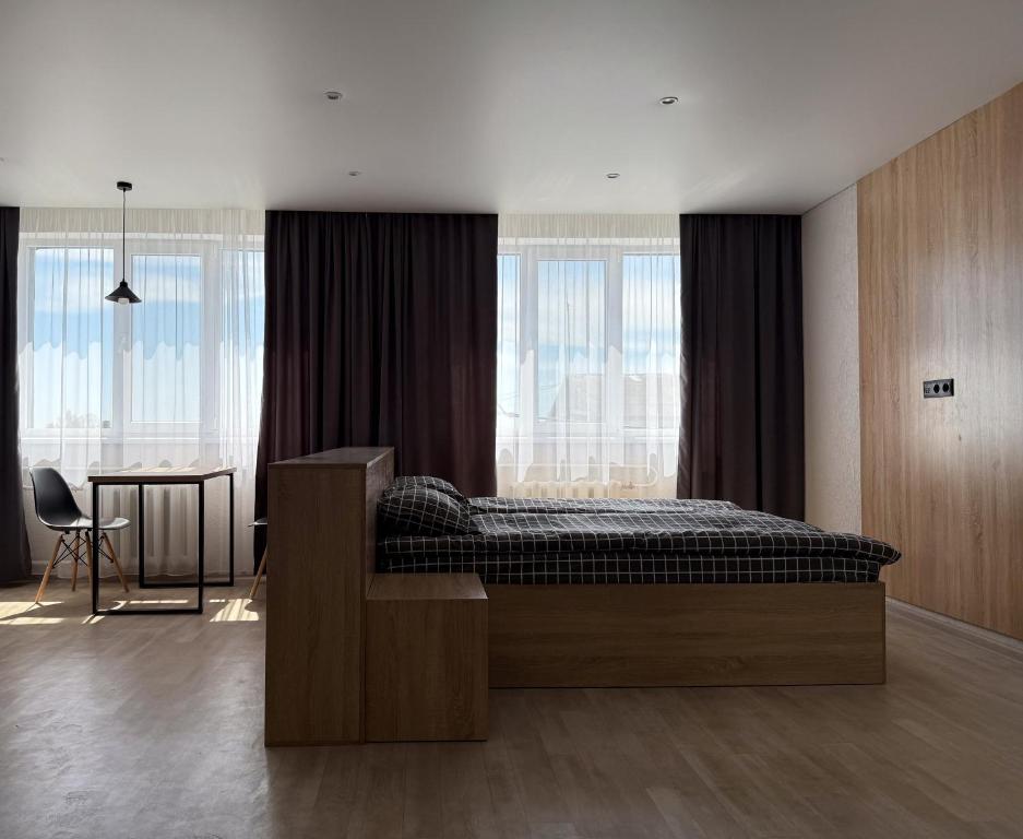 une chambre avec un lit, une table et des fenêtres dans l'établissement Поділля, à Netishyn