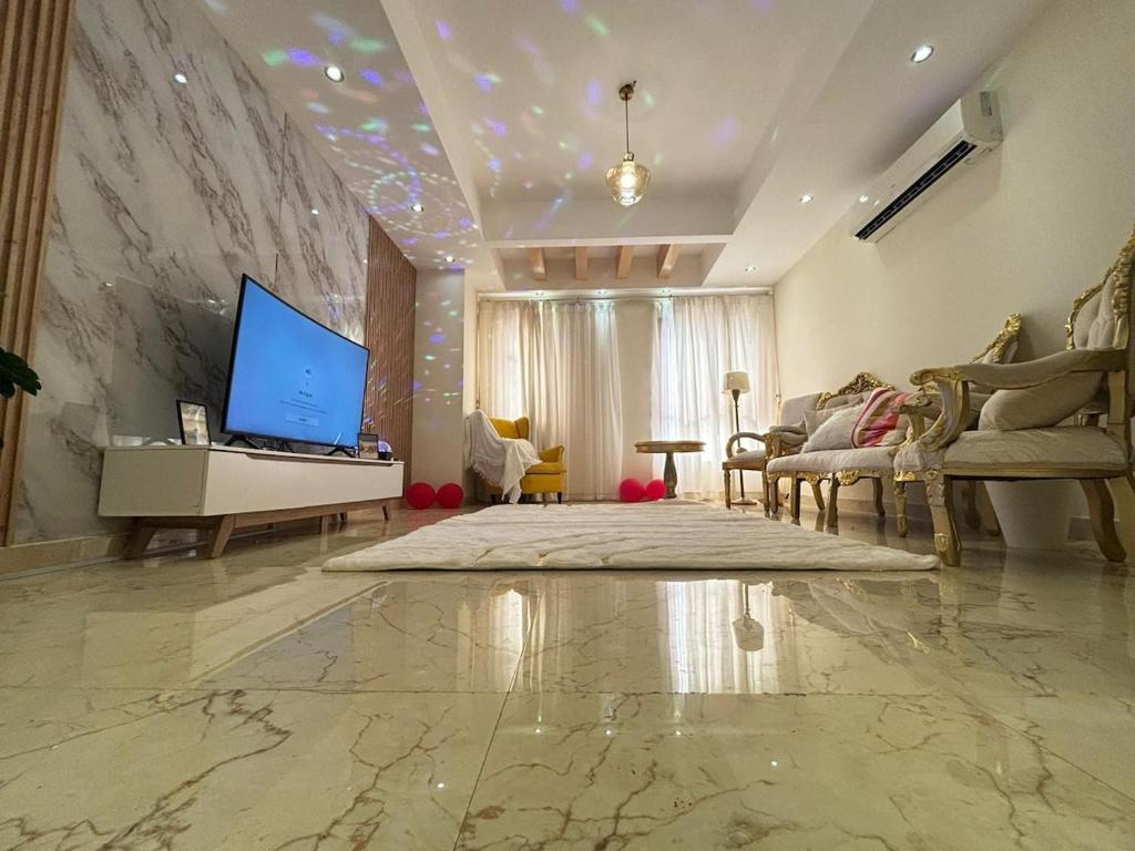 ein Wohnzimmer mit Fernseher und ein Wohnzimmer mit Sofa in der Unterkunft Opera413 Spacious & Central in Muscat