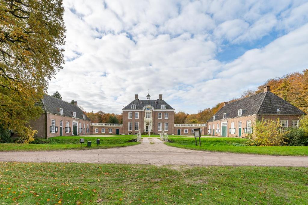 Un gran edificio de ladrillo con una calle enfrente. en De Zwaluwenburg, en 't Harde