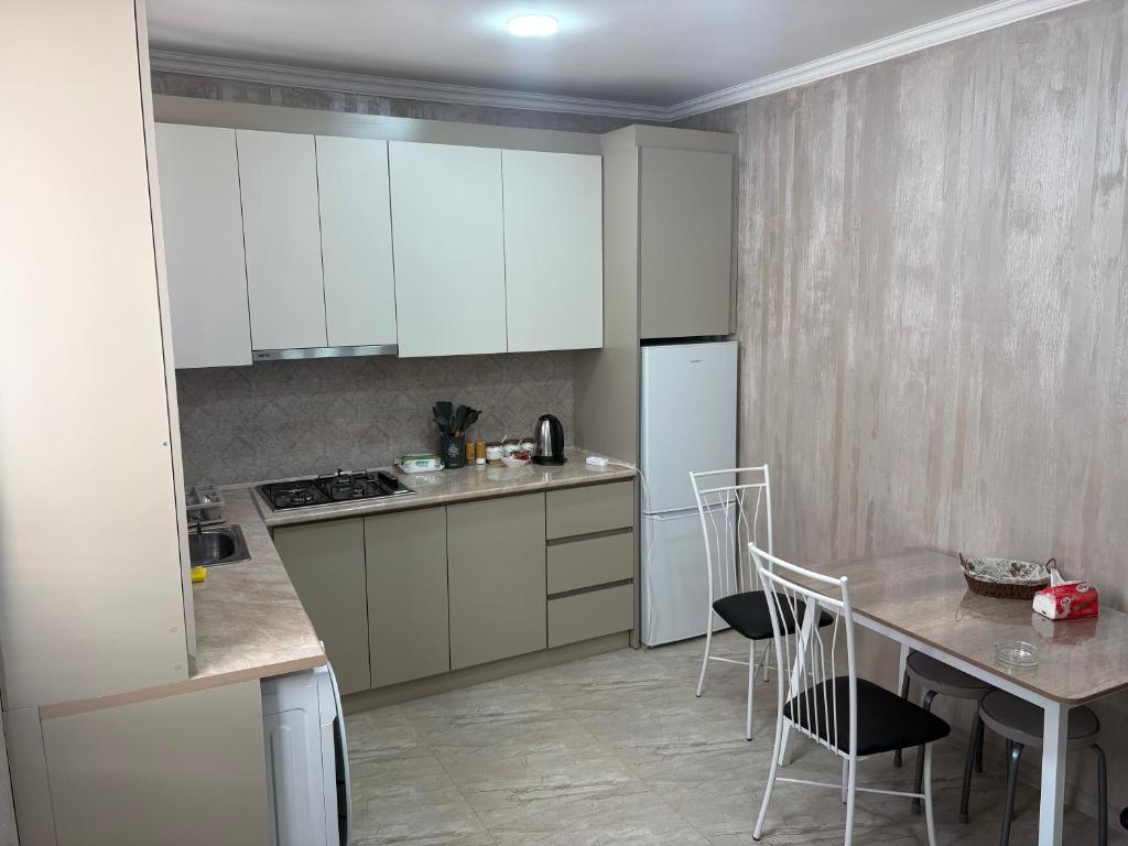 ギュムリにあるHyuratunの白いキャビネットとテーブルと椅子のあるキッチン