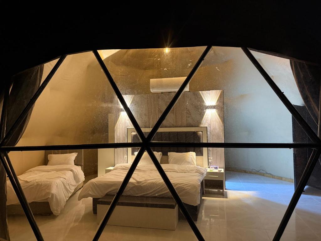Wadi Rum Sunset camp في Disah: سريران في غرفة بها نافذة