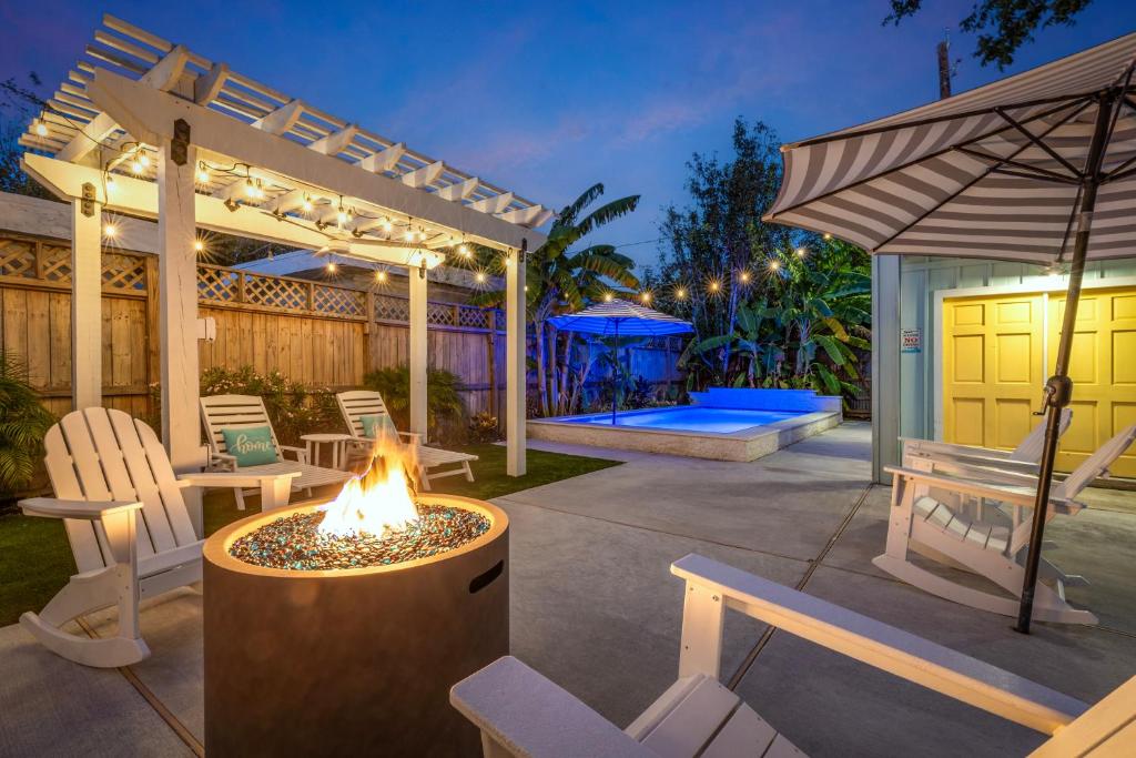 een achtertuin met een vuurplaats met stoelen en een parasol bij Historic 1926 Summerwind with Heated Pool - 3 Blocks to Beach in Galveston