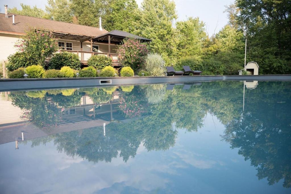 a house with its reflection in a swimming pool at Private 5-Acre Retreat In-Ground Pool Hot Tub in Oberlin