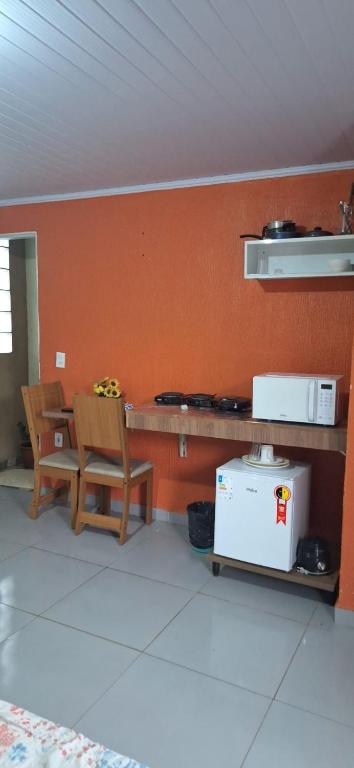 a kitchen with a counter and two chairs and a table at Hospedagem da Fran in Brasília