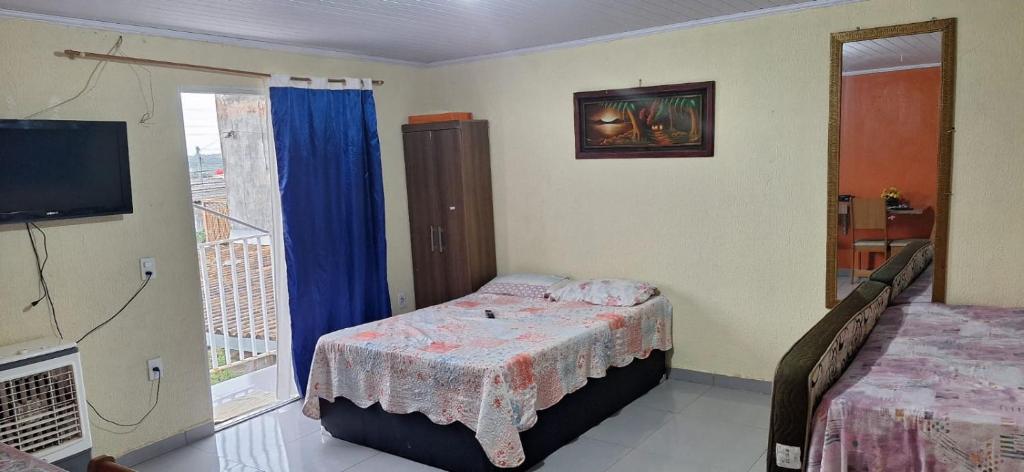 a bedroom with a bed and a balcony with a television at Hospedagem da Fran in Brasilia