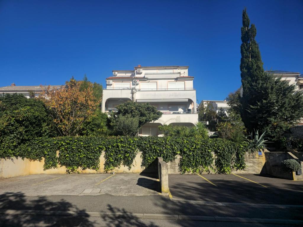 a white building with a lot of bushes and trees at Apartmani Vanessa in Dramalj