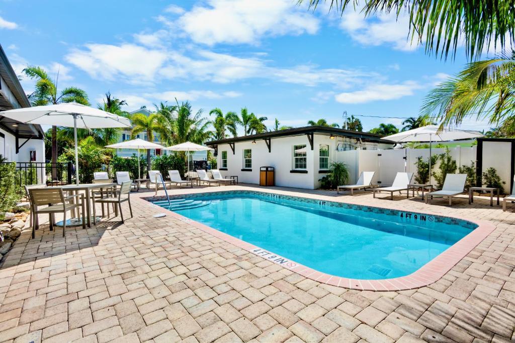 a pool with chairs and umbrellas next to a house at Haley's at Anna Maria Island Inn in Holmes Beach