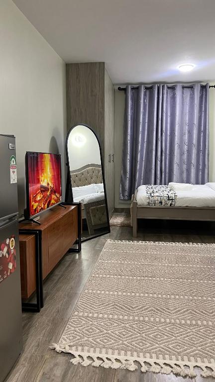a bedroom with a bed and a tv and a mirror at Amber Home Ruaka Near Two Rivers Mall & UN in Ruaka