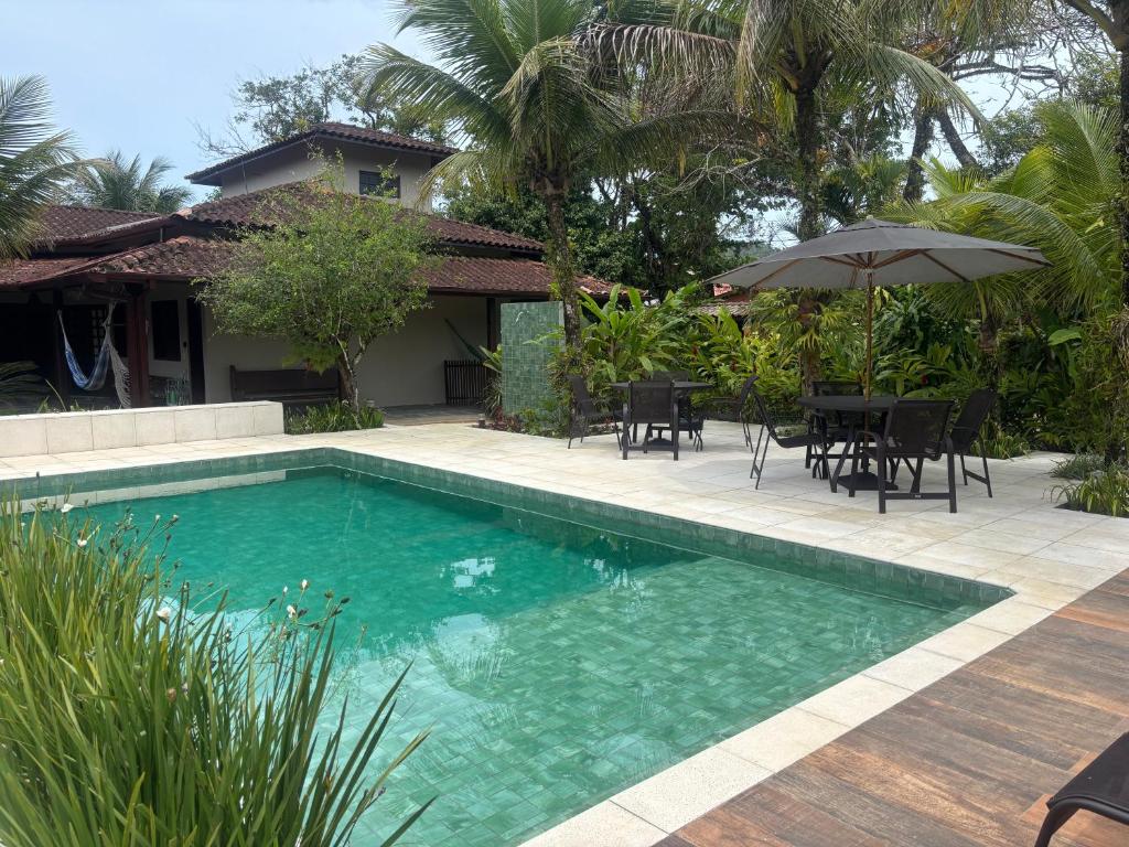 een zwembad met stoelen en een parasol naast een huis bij Itamambuca Suites in Ubatuba