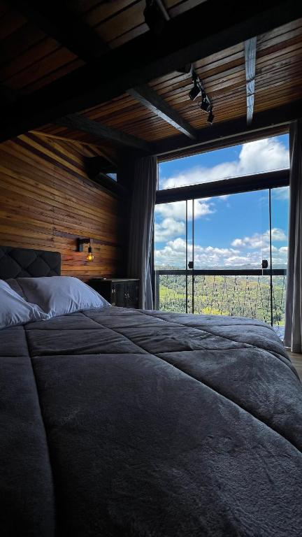 a bedroom with a large bed with a large window at The Valley Cabin in Alfredo Wagner