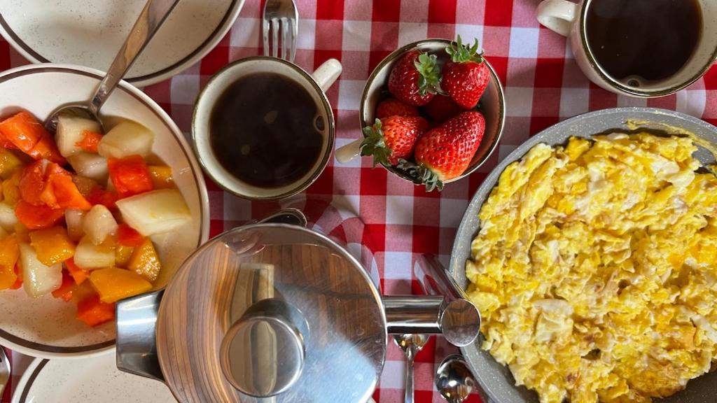a table with a breakfast of eggs and strawberries at The Valley Cabin in Barracão