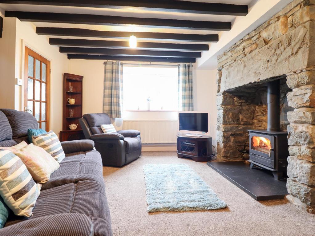 a living room with a couch and a stone fireplace at Bryn Re in Trawsfynydd