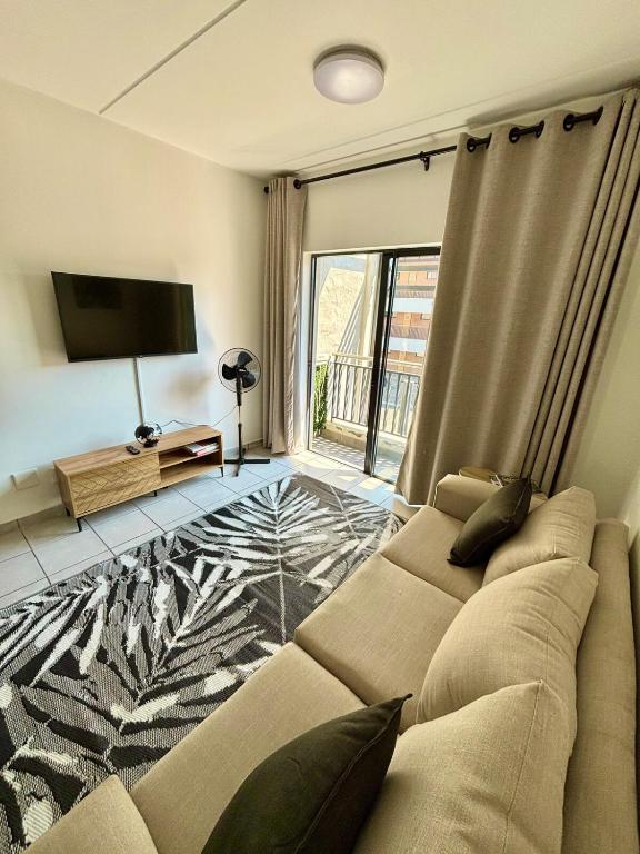 a living room with a couch and a television at Waterfall Smart Apartment 2bed2bath in Midrand