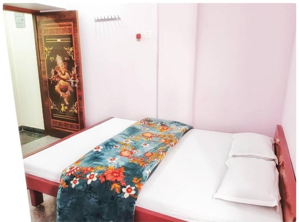 een kleine kamer met een bed met een bloemendeken erop bij Sri Hotel Ganga in Patna