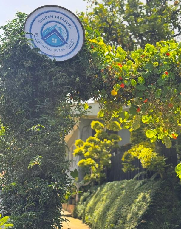 a sign for a house with some bushes and flowers at Hidden Treasure in Nuwara Eliya