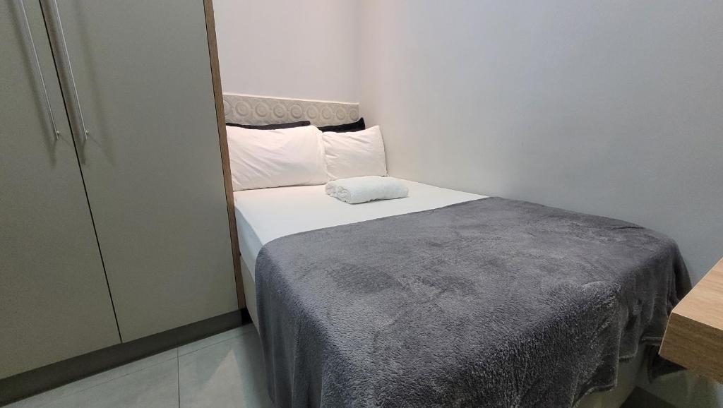 een kleine slaapkamer met een bed met witte lakens en kussens bij Residencial Hanna in Anápolis