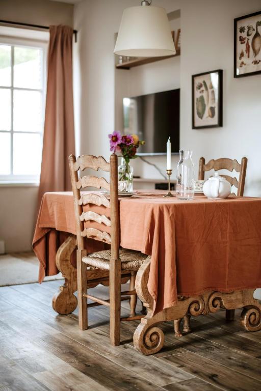 a dining room with a table with a vase of flowers at Gîte de la maraîchère in Ittre