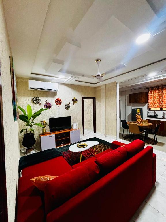 a living room with a red couch and a table at Modern 2-Bedroom Apt with African Vibe- Cape Coast in Cape Coast