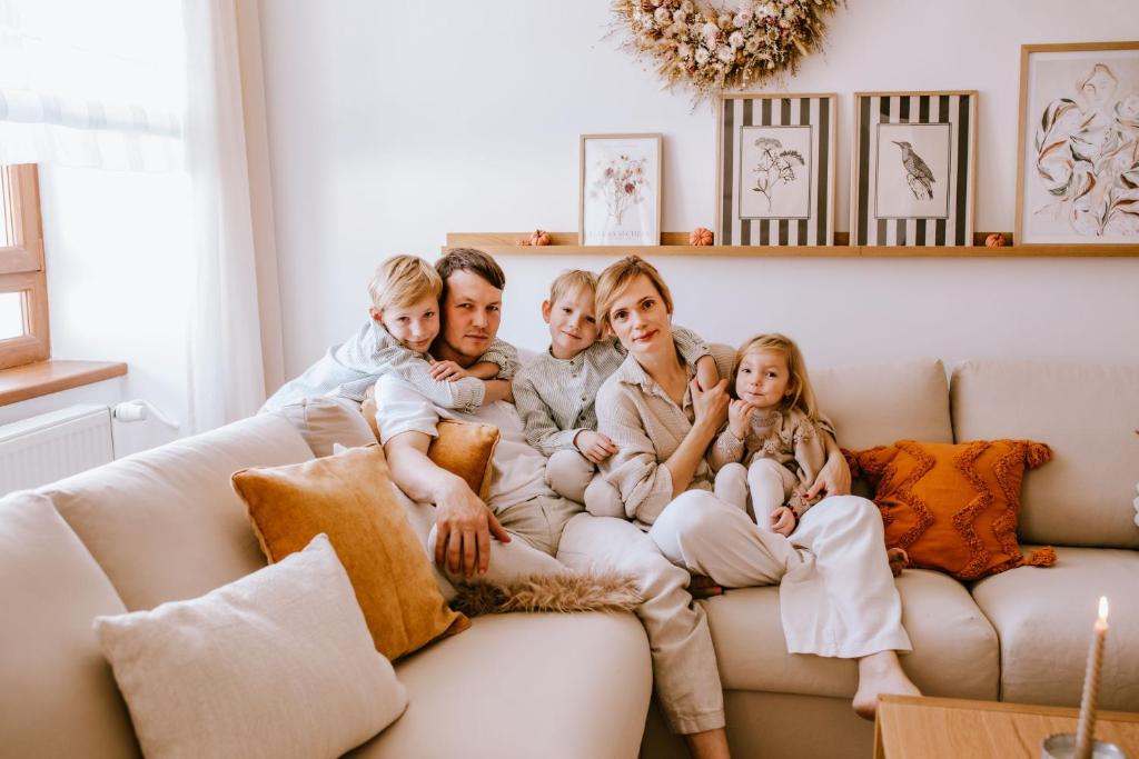 a family sitting on a couch in a living room at JUGA Apartmány in Jaroslavice