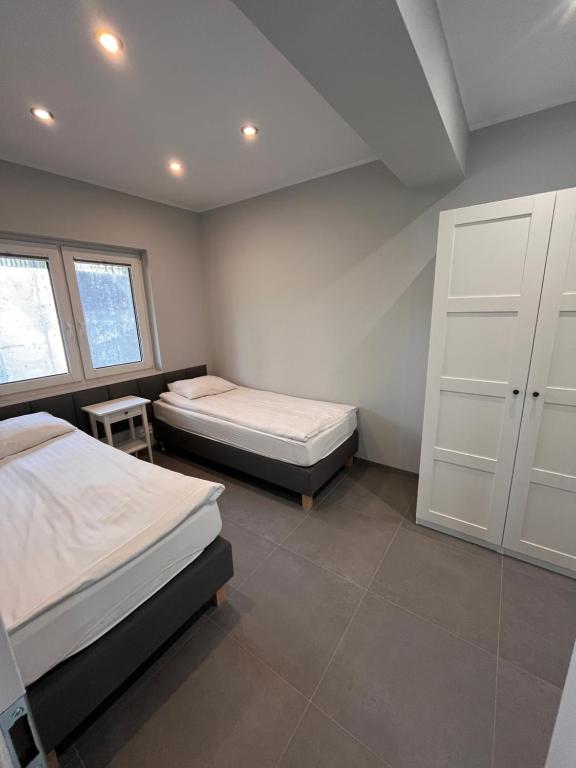 a bedroom with two beds and a white cabinet at Domy całoroczne Cieszyno in Cieszyno