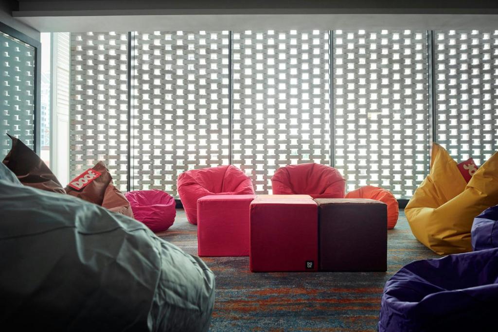 A colourful casual seating nook filled with beanbags and low cube seats beside patterned windows.