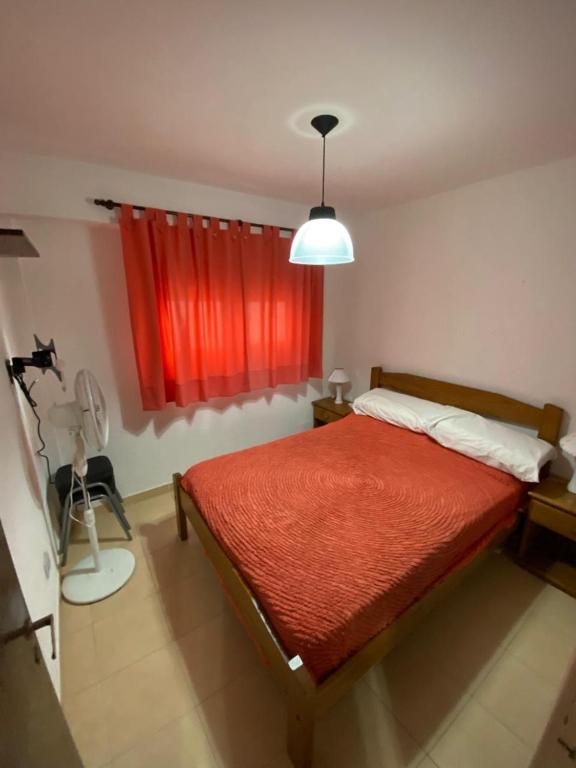a bedroom with a bed with a red curtain at Mar de Ana, Frente al mar, interno a una cuadra del centro in San Bernardo