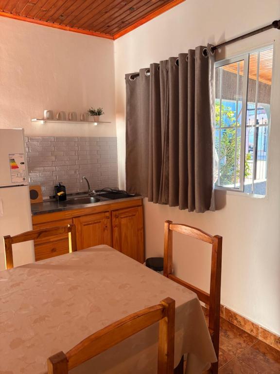 Una cocina con una mesa y un fregadero y una ventana. en Las Azaleas, en Puerto Iguazú