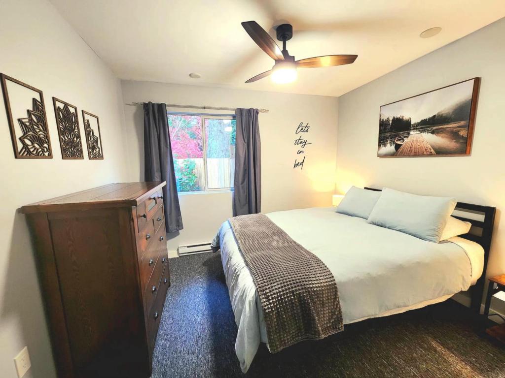 een slaapkamer met een bed en een plafondventilator bij Modern 2BR SPA Retreat in Shawnigan Lake