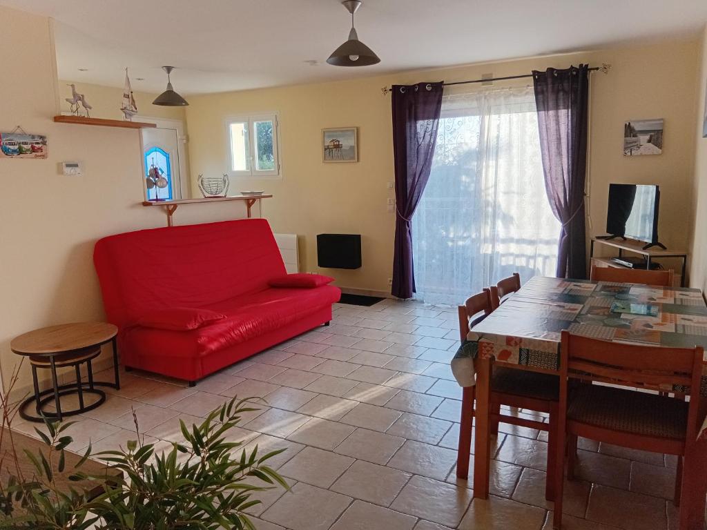 een woonkamer met een rode bank en een tafel bij Logement Soulac sur mer in Soulac-sur-Mer
