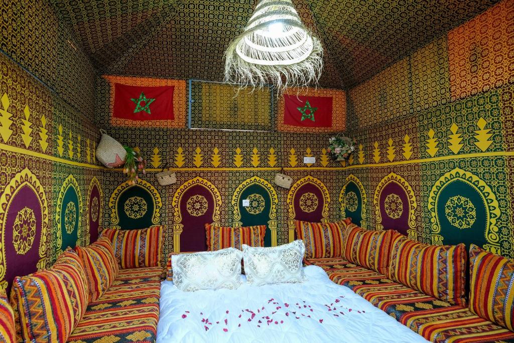 een slaapkamer met een bed en stoelen in een kamer bij Studio traditionnel amazigh marocain in Benguerir