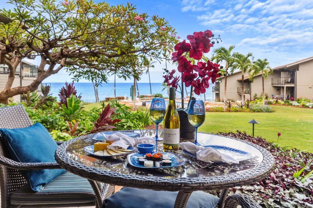 a table with a bottle of wine and a plate of food at Mahina Surf 117 in Kapalua
