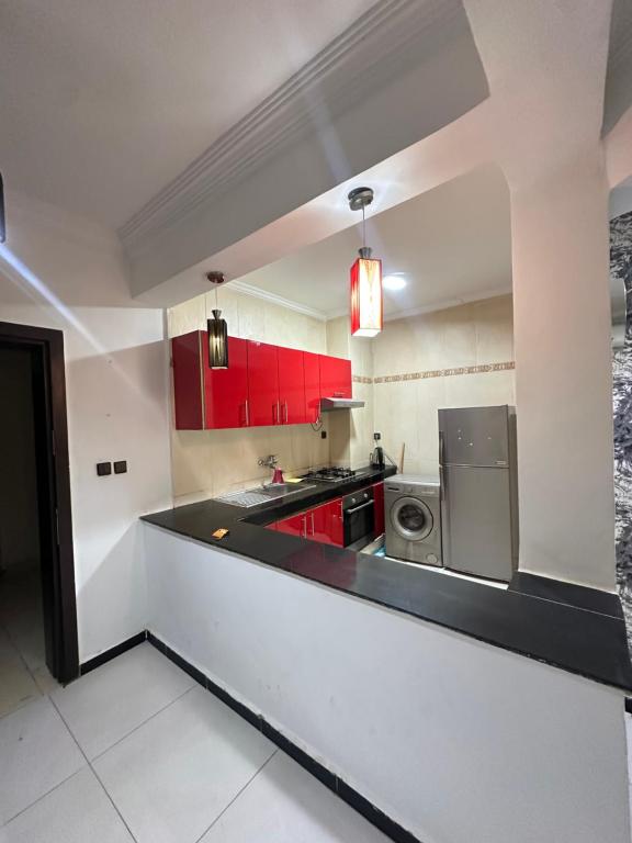 cocina con armarios rojos y fogones en Beachfront bliss, en Tánger