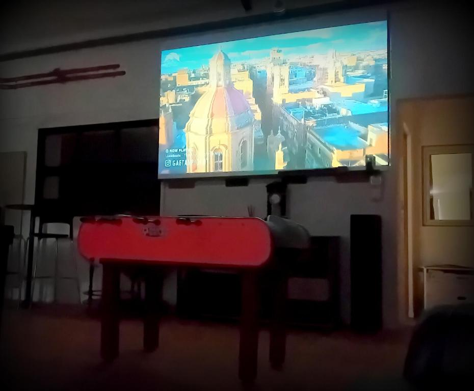un televisor de pantalla grande con una mesa roja delante. en Le Moulin Neuf, en Anetz