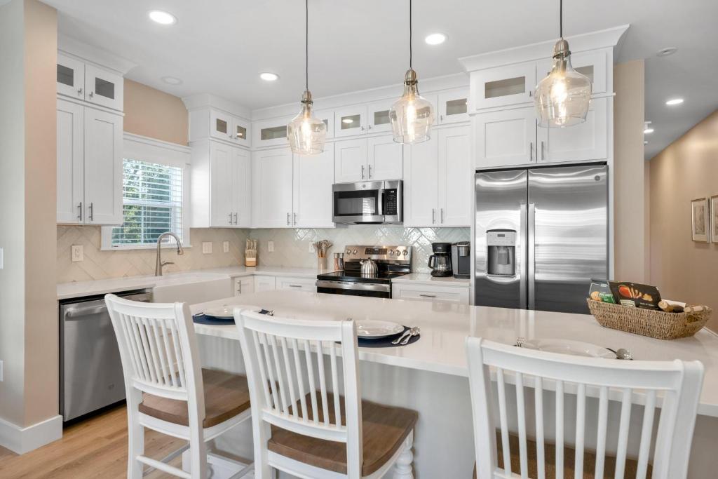 a kitchen with white cabinets and a island with chairs at 240 Olive Shell Court in Hilton Head Island