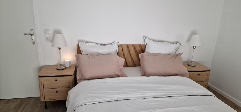 ein Schlafzimmer mit einem Bett mit Kissen und zwei Lampen in der Unterkunft Hebergement DEUX pièces en résidence propre et calme in Lieusaint
