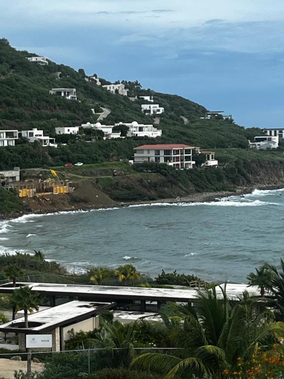 a view of the ocean with houses on a hill at Indigo Escape in Koolbaai