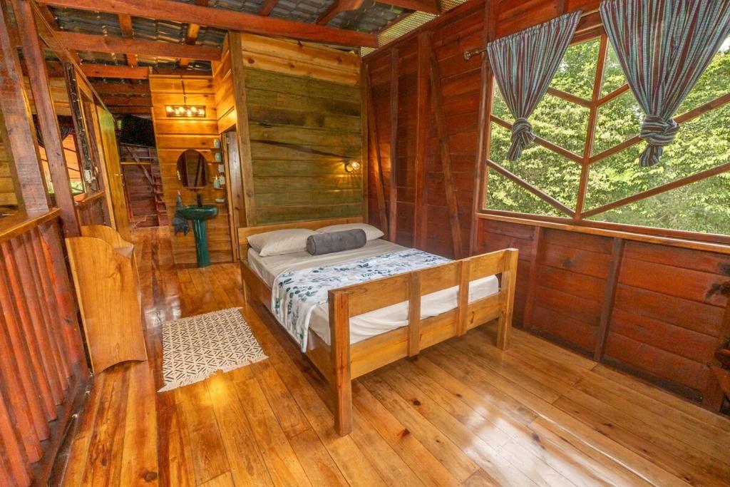 1 dormitorio en una cabaña de madera con cama y ventana en Utopia Bluff Beach Off Grid Jungle Retreat By The Sea, en Bocas Town