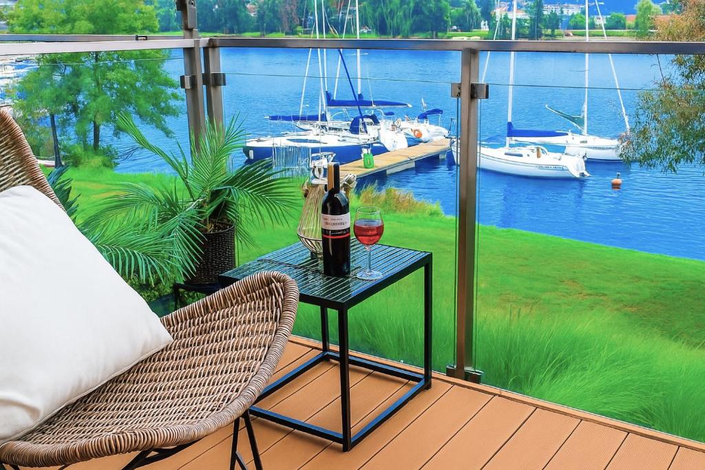 een patio met een tafel met 2 glazen wijn bij Marina Relax - widok na jezioro, parking podziemny, winda, Netflix, TV55" in Iława