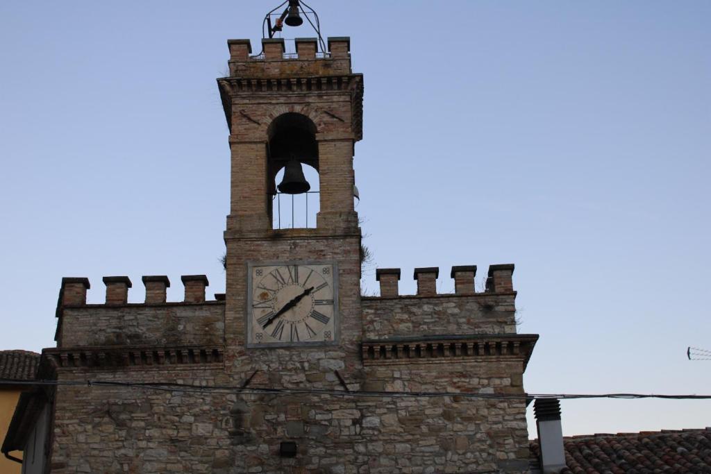 a clock tower with a bell and a clock on it at La Piazzetta Apartment in Pietralunga