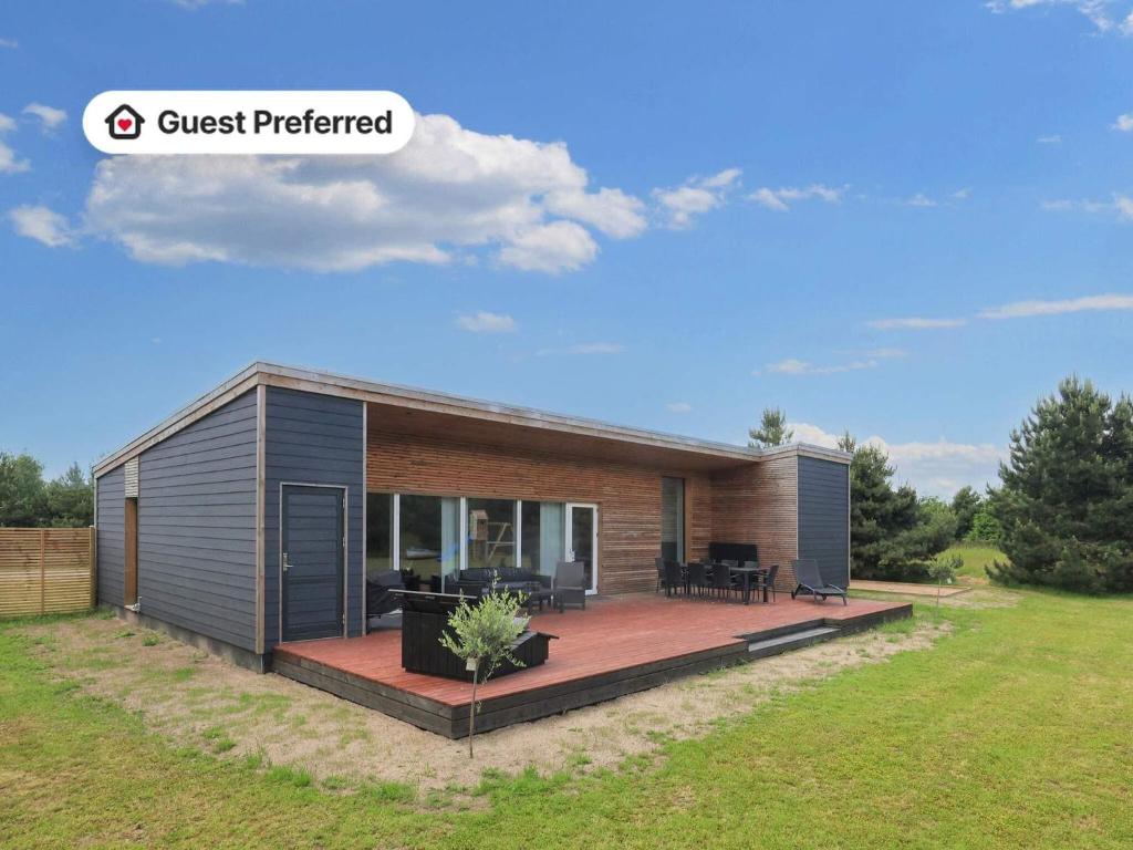 a small house with a wooden deck in a field at 4 star holiday home in Væggerløse-By Traum in Marielyst