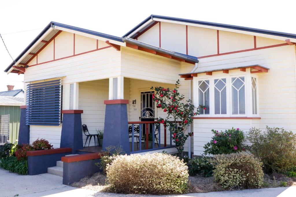 ein weißes Haus mit einer Veranda mit Blumen in der Unterkunft Heritage Home with BBQ & Outdoor Fire Pit in Tenterfield