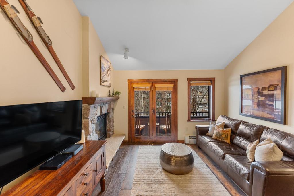 ein Wohnzimmer mit einem Ledersofa und einem TV in der Unterkunft Arapahoe Lodge 8137 in Snake River Health Services Incorporated Heliport