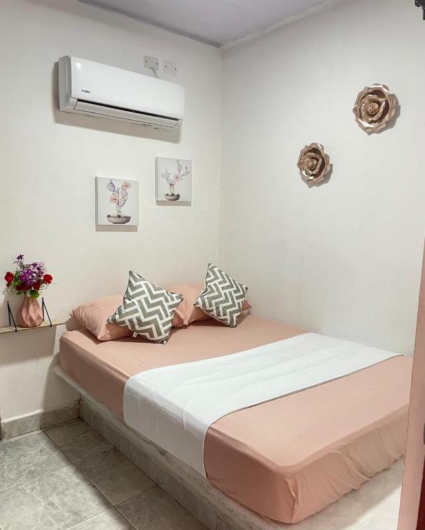 een slaapkamer met een bed met roze en witte kussens bij hotel Siboney - Centro in Estación El Salto