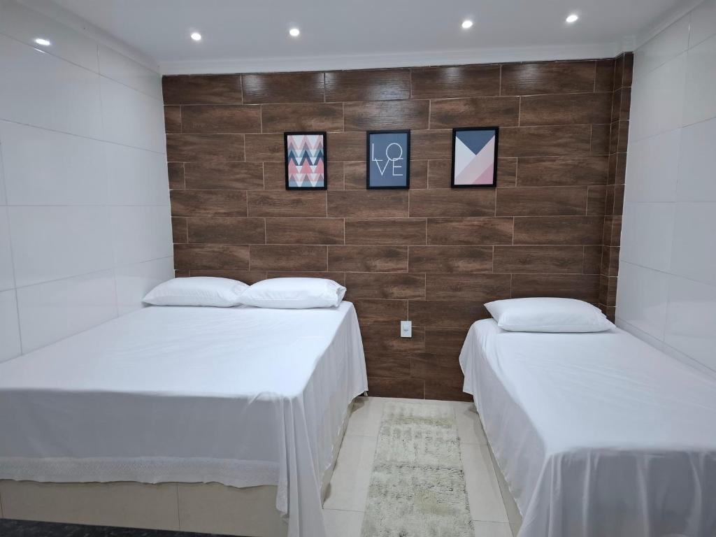 deux lits dans une chambre avec des draps blancs dans l'établissement Refúgio Fontana, à Santa Teresa